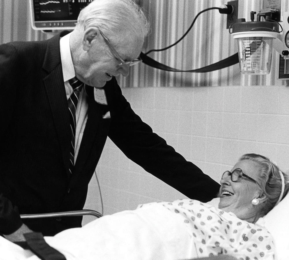 Thomas Frist Sr. at a bed talking to a patient
