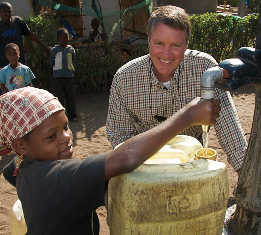 Bill First helps a child with a water tap
